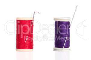 Two red and purple thread bobbin and needle