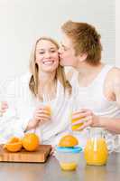 Breakfast kissing couple enjoy orange juice