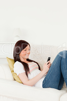 Good looking red-haired woman writing a text on her phone while