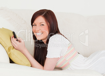 Good looking red-haired female writing a text on her phone