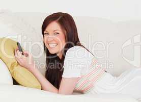 Good looking red-haired female writing a text on her phone