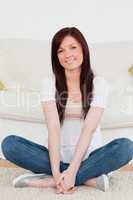 Smiling red-haired woman posing while sitting on a carpet