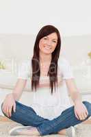 Attractive red-haired woman posing while sitting on a carpet