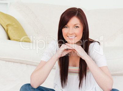 Good looking red-haired woman posing while sitting on a carpet