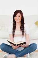 Good looking red-haired woman reading a book while sitting on a