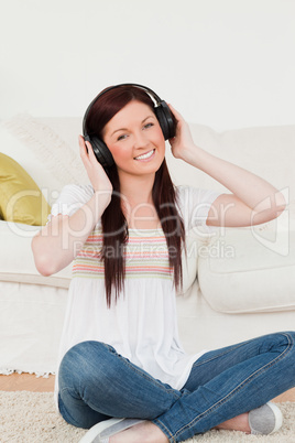 Good looking red-haired woman listening to music with headphones