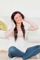 Attractive red-haired woman listening to music with headphones w