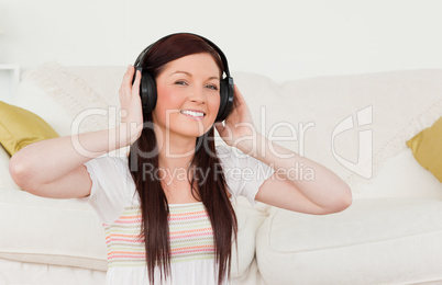 Beautiful red-haired woman listening to music with headphones wh