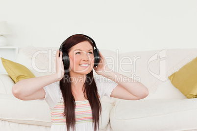 Pretty red-haired woman listening to music with headphones while