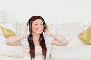 Pretty red-haired woman listening to music with headphones while
