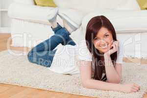 Attractive red-haired woman posing while lying on a carpet