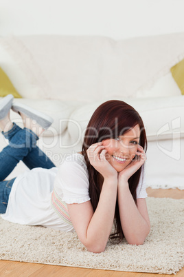 Gorgeous red-haired woman posing while lying on a carpet