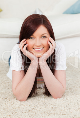 Attractive red-haired female posing while lying on a carpet