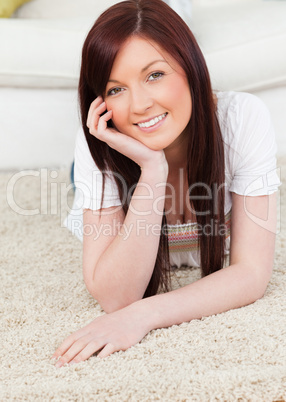 Beautiful red-haired female posing while lying on a carpet