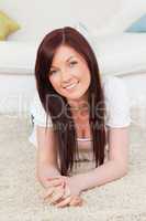Good looking red-haired female posing while lying on a carpet