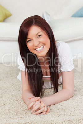 Pretty red-haired female posing while lying on a carpet