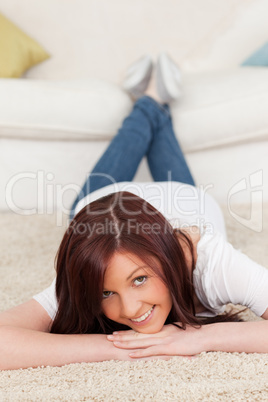 Gorgeous red-haired female posing while lying on a carpet