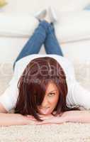 Joyful red-haired female posing while lying on a carpet