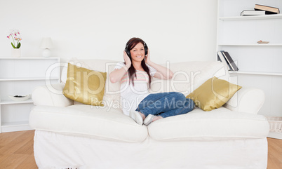 Attractive red-haired female listening to music with headphones