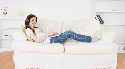 Beautiful red-haired female listening to music with headphones w