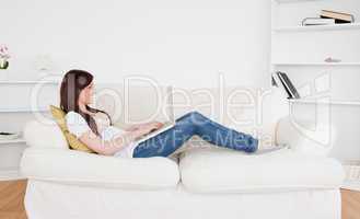 Beautiful red-haired female relaxing with her laptop while lying