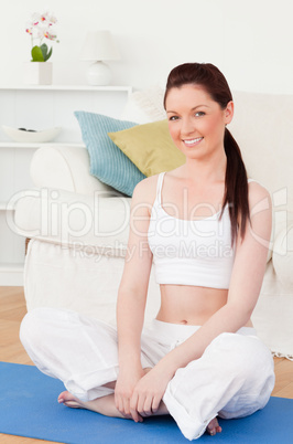 Young woman posing while sitting on a gym carpet