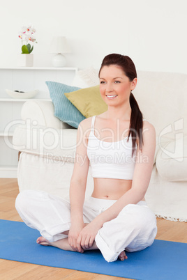 Beautiful woman posing while sitting on a gym carpet