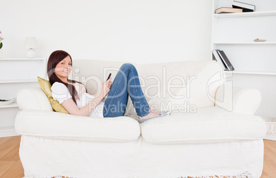 Good looking red-haired female writing a text on her phone while