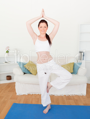 Attractive red-haired woman stretching in the living room