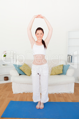 Good looking red-haired woman stretching in the living room