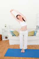 Charming red-haired woman stretching in the living room