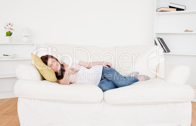 Attractive red-haired female watching tv while lying on a sofa