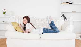 Gorgeous red-haired female posing while lying on a sofa