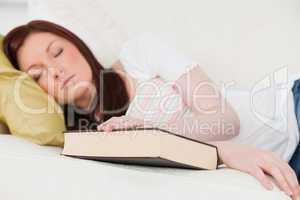 Good looking red-haired girl having a rest while studying on a s