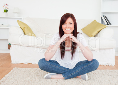 Attractive red-haired female posing while sitting on a carpet