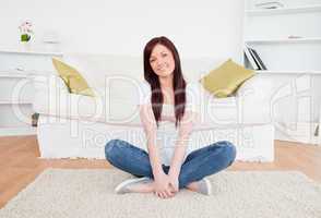 Good looking red-haired female posing while sitting on a carpet