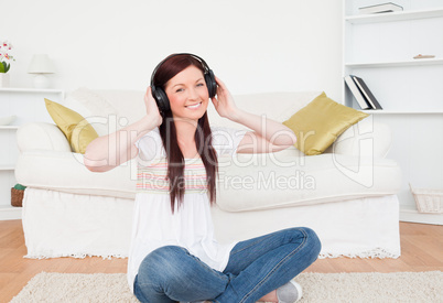Attractive red-haired female listening to music with headphones