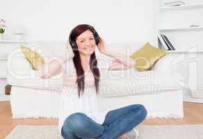 Attractive red-haired female listening to music with headphones