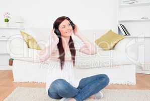 Good looking red-haired female listening to music with headphone