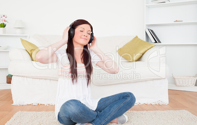 Beautiful red-haired female listening to music with headphones w