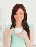Attractive red-haired woman having her breakfast in the kitchen