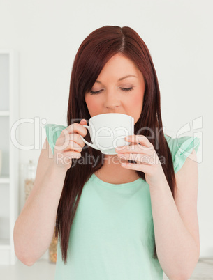 Beautiful red-haired woman having her breakfast in the kitchen