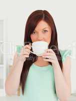 Good looking red-haired woman having her breakfast in the kitche