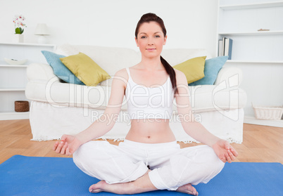 Beautiful female doing yoga on a gym carpet