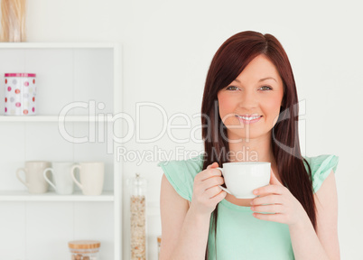 Charming red-haired woman having her breakfast in the kitchen