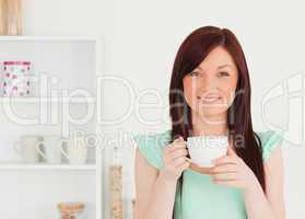 Charming red-haired woman having her breakfast in the kitchen
