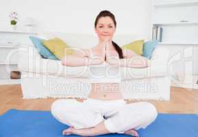 Pretty female doing yoga on a gym carpet