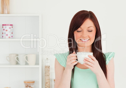 Cute red-haired woman having her breakfast in the kitchen