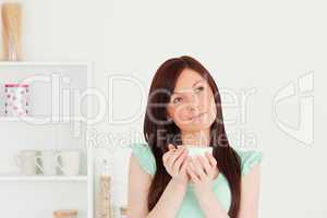 Pretty red-haired woman enjoying her breakfast in the kitchen