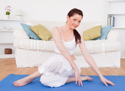 Attractive red-haired female stretching in the living room